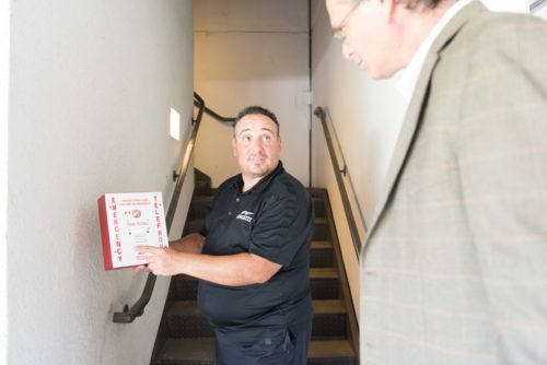 Kings III Representative displaying an emergency phone box to a client in front of a stairwell